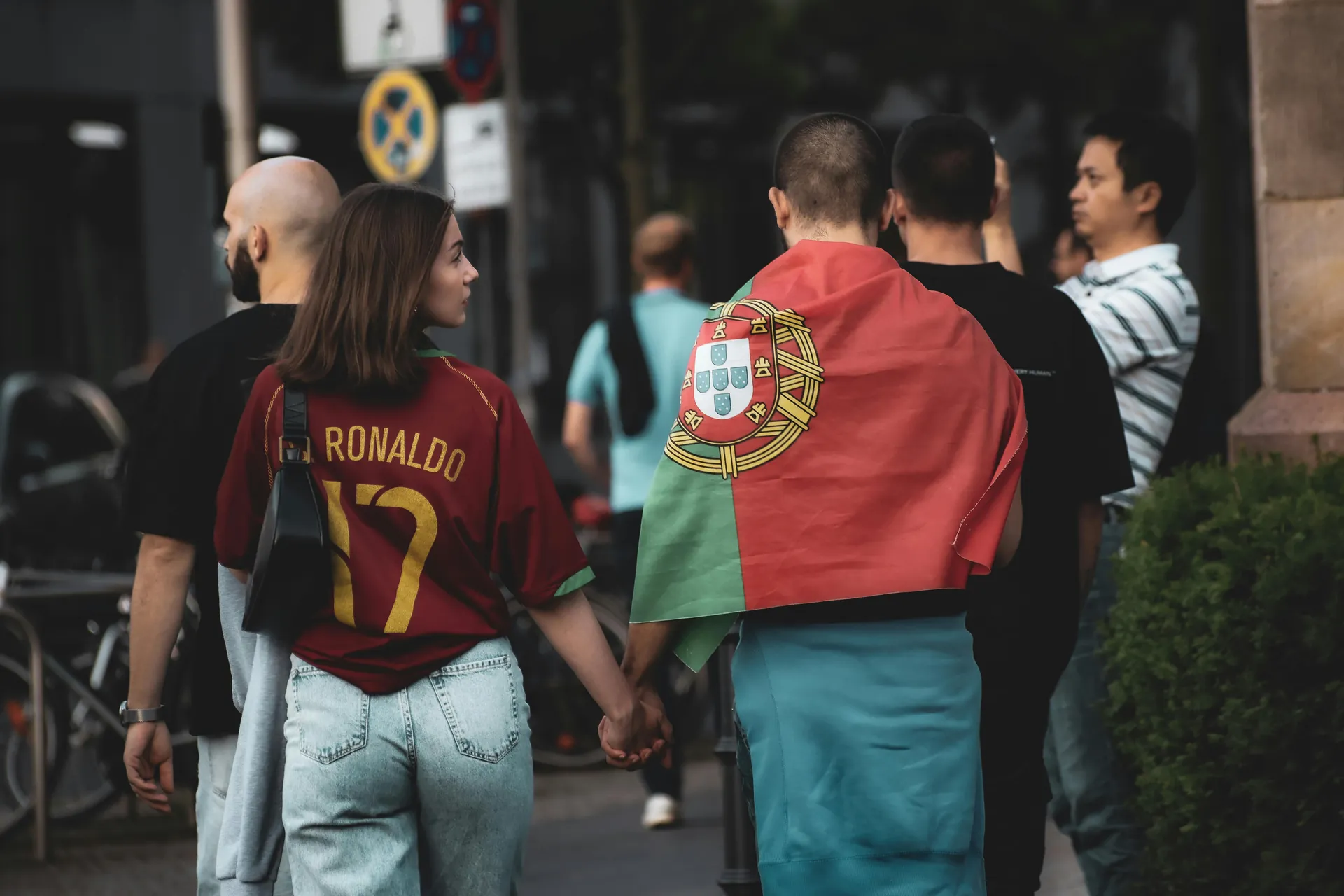 Una pareja caminando de la mano; ella lleva una camiseta retro de Portugal con el apellido Ronaldo